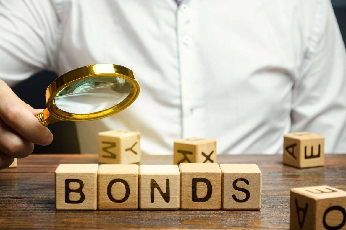 債券ETF|一個人手拿放大鏡,前面有積木上面寫著BONDS